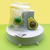 Avocado catnip toy displayed with packaging on a white pedestal against a yellow background.